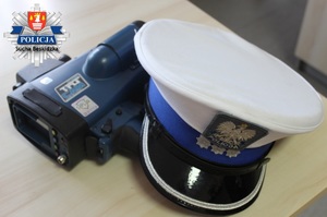 czapka policyjna policjanta ruchu drogowego i laserowy miernik prędkości położony na stoliku