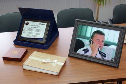 Zdjęcie przedstawia ułożone na stole upominki dla odchodzącego na emeryturę dyżurnego w postaci jego zdjęcia w ramce, albumu z pamiątkowymi zdjęciami oraz upominku zarządu terenowego niezależnych związków zawodowych