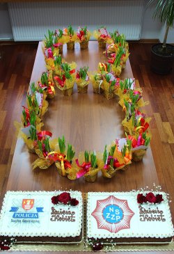 ósemka z kwiatów ułożona na stole przed dwoma tortami z okazji dnia kobiet