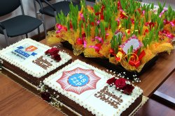 zdjęcie przedstawiające dwa torty jeden z logo KPP Sucha Beskidzka a drugi z logiem związków zawodowych Policji na tle kwiatów dla wszystkich kobiet