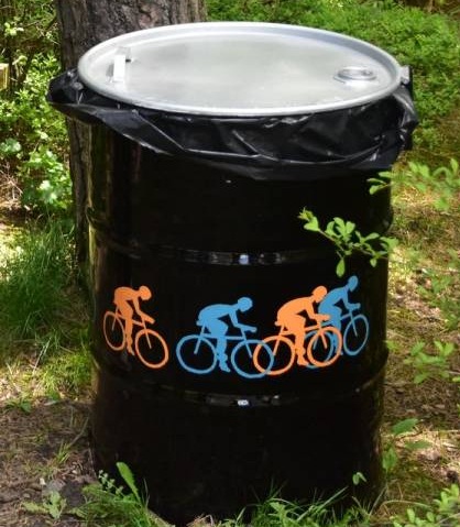 kosz na odpady koloru czarnego z namalowanymi rowerzystami w kolorze niebieskim i pomarańczowym
