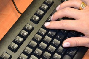 Dłoń kobiety klikająca po klawiaturze komputera
