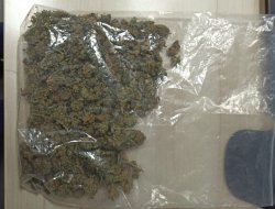 zdjęcie przedstawia ususzoną marihuanę zebraną do foliowego worka położonego na stoliku