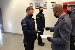 Zastępca Komendanta Powiatowego Policji ściskając jednemu z nowych policjantów rękę gratuluje i wręcza odznakę służbową