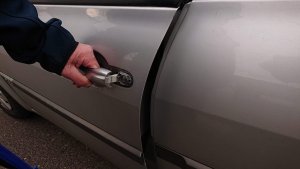 dłoń męska trzymająca za klamkę od drzwi samochodu koloru srebrnego
