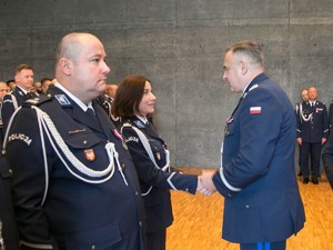 Komendant Wojewódzki Policji w Krakowie ściskający rękę starszej Pani oficer