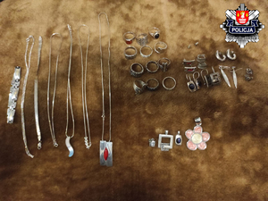 srebrna i złota biżuteria w postaci naszyjników z wisiorkami i pierścionkami oraz kolczykami położone na stole