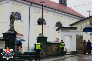 policjanci stojący z odblaskami przy bramie wejściowej na teren kościoła w Makowie Podhalańskim