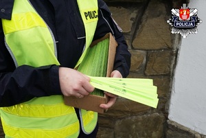 policjantka trzymająca opaski odblaskowe do rozdania na których widnieje napis maków podhalański i logo makowa