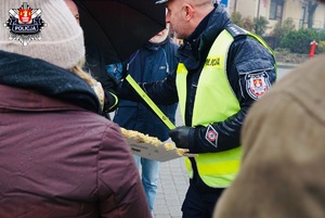 policjant ruchu drogowego wręczający opaski odblaskowe