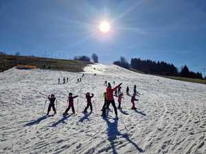 instruktor i mali narciarze rozgrzewający się na stoku narciarskim w Zawoi