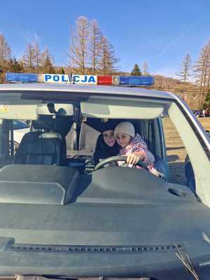dziewczynka i chłopczyk siedzący za kierownica policyjnego radiowozu