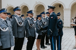 policjantka stojąca  wśród policjantów odbierająca rozkaz na wyższy stopień policyjny