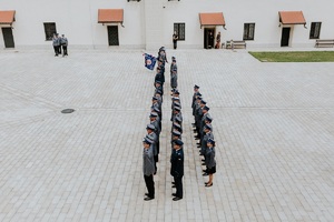 stojacy w szeregu policjanci i poczet z upuszczonym sztandarem