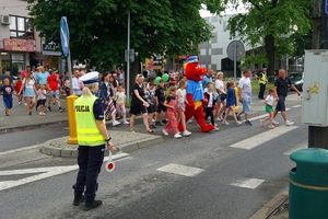 Policjanci wstrzymujący ruch i przechodzący przez pasy policek wraz z dziećmi i ich rodzicami