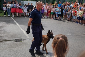 Przewodnik wraz z psem służbowym pozuje do zdjęcia wśród uczestników pikniku