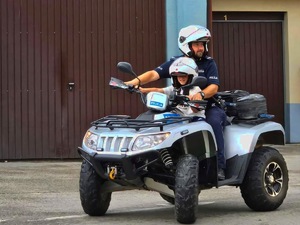 Dziecko jadące w kasku z policjantem na policyjnym quadzie