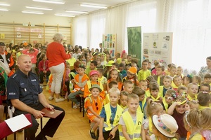 naczelnik WRD suskiej komendy siedzący wśród dzieci przed odblaskowym pokazem mody