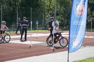 rowerzyści na torze i oceniający ich obok policjanci