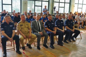 Pan Komendant Powiatowy Policji w Suchej Beskidzkiej siedzący wraz z innymi policjantami oraz komendantem straży i przewodniczącym związków podczas rozdania pucharów