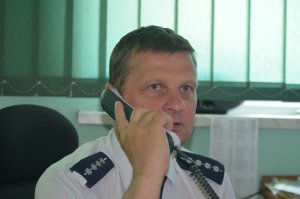 Zdjęcie przedstawiające aspiranta sztabowego jacka rusa trzymającego słuchawkę telefoniczną na stanowisku dowodzenia komendy powiatowej policji w suchej beskidzkiej