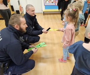 Dzielnicowi wręczający wszystkim uczestnikom spotkania opaski odblaskowe