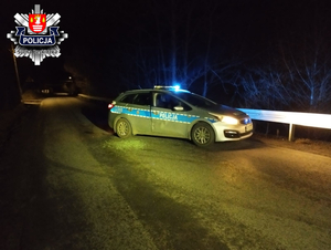 oznakowany radiowóz z uszkodzonymi bocznymi drzwiami stojący bokiem na drodze