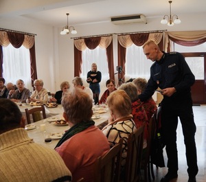 Policjant wręczający magnesy seniorom.