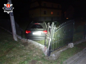 czarny samochód i uszkodzone ogrodzenie