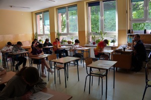 Uczniowie z jednej z grup siedzący w ławkach i rozwiązujący zadania