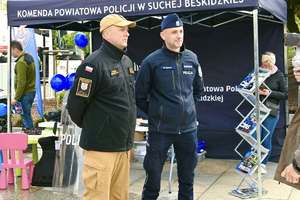 Rzecznik suskiej policji i suskiej straży pożarnej przed stoiskiem KPP w Suchej Beskidzkiej
