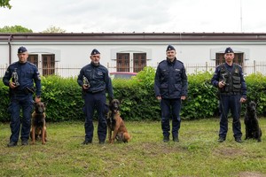przewodnicy z psami pozujący do zdjęcia z trofeami
