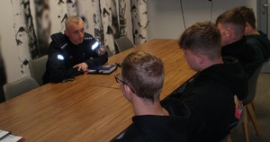 policjant siedzący przy stole z młodzieżą z OHP Wadowice