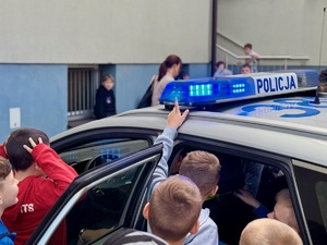 chłopiec ręką próbuje dotknąć policyjna belkę sygnałową na dachu radiowozu