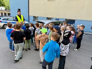 policjant stojący przy radiowozie a przed nim grupka dzieci