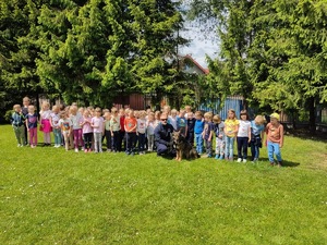 wspólne pamiątkowe zdjęcie  psa policyjnego wraz z opiekunem i przedszkolaków