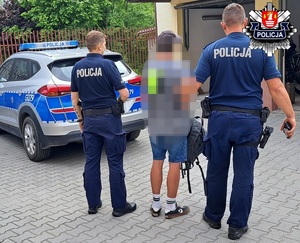 policjanci trzymający podejrzewanego przy radiowozach