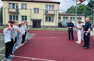 dzieci na orliku słuchające policjantów podczas pogadanki