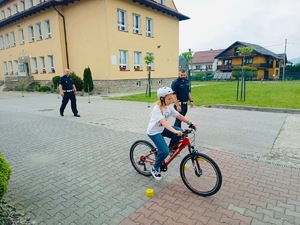 dziewczynka na rowerze i stojący za nią policjanci