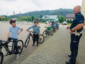 policjant stojący przed dziećmi na rowerach