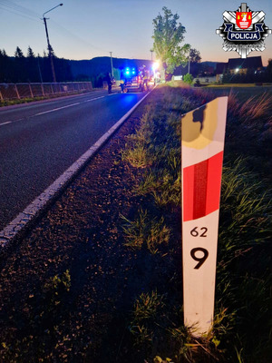 słupek hektometryczny na tle pojazdów służbowych na drodze