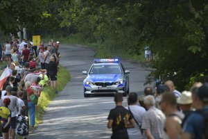 radiowóz oznakowany jadący drogą pośród ludzi zgromadzonych na poboczu