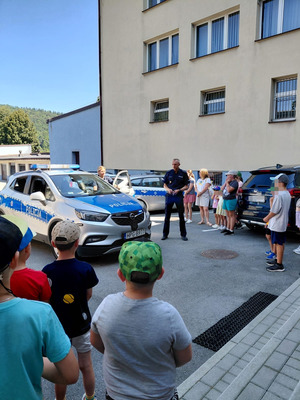 dzieci stojące wokół policyjnego radiowozu z policjantem
