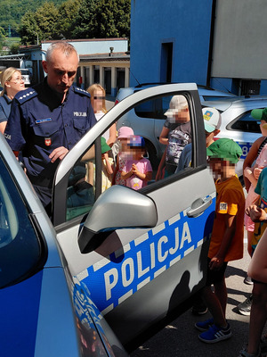 Grupa dzieci w obecności policjantów oglądające wnętrze radiowozu