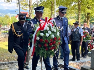 Idący z wieńcem Zastępca Komendanta Powiatowego Policji w Suchej Beskidzkiej wraz z Komendantem Komisariatu Policji w Jordanowie oraz komendantem Powiatowym Państwowej Straży Pożarnej