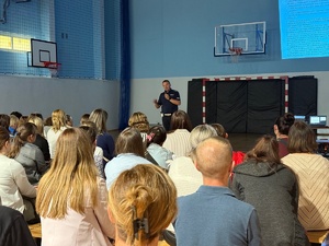 Policjant ruchu drogowego na hli sportowej prowadzący zajęcia dla rodziców