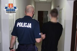 umundurowany policjant trzymający zatrzymanego za lewą rękę w pdoz