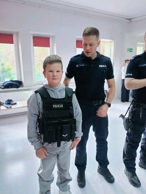 Chłopiec z założoną kamizelką policyjną