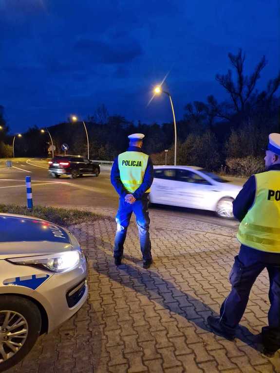 policjanci drogówki przyglądają się jadącym drogą kierowcom