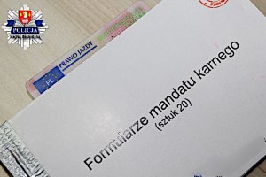 zdjęcie przedstawia pierwsza stronę formularzy mandatów karnych wraz włożonym do środka blankietem prawa jazdy oraz logiem kpp sucha beskidzka po prawej górnej stronie zdjęcia